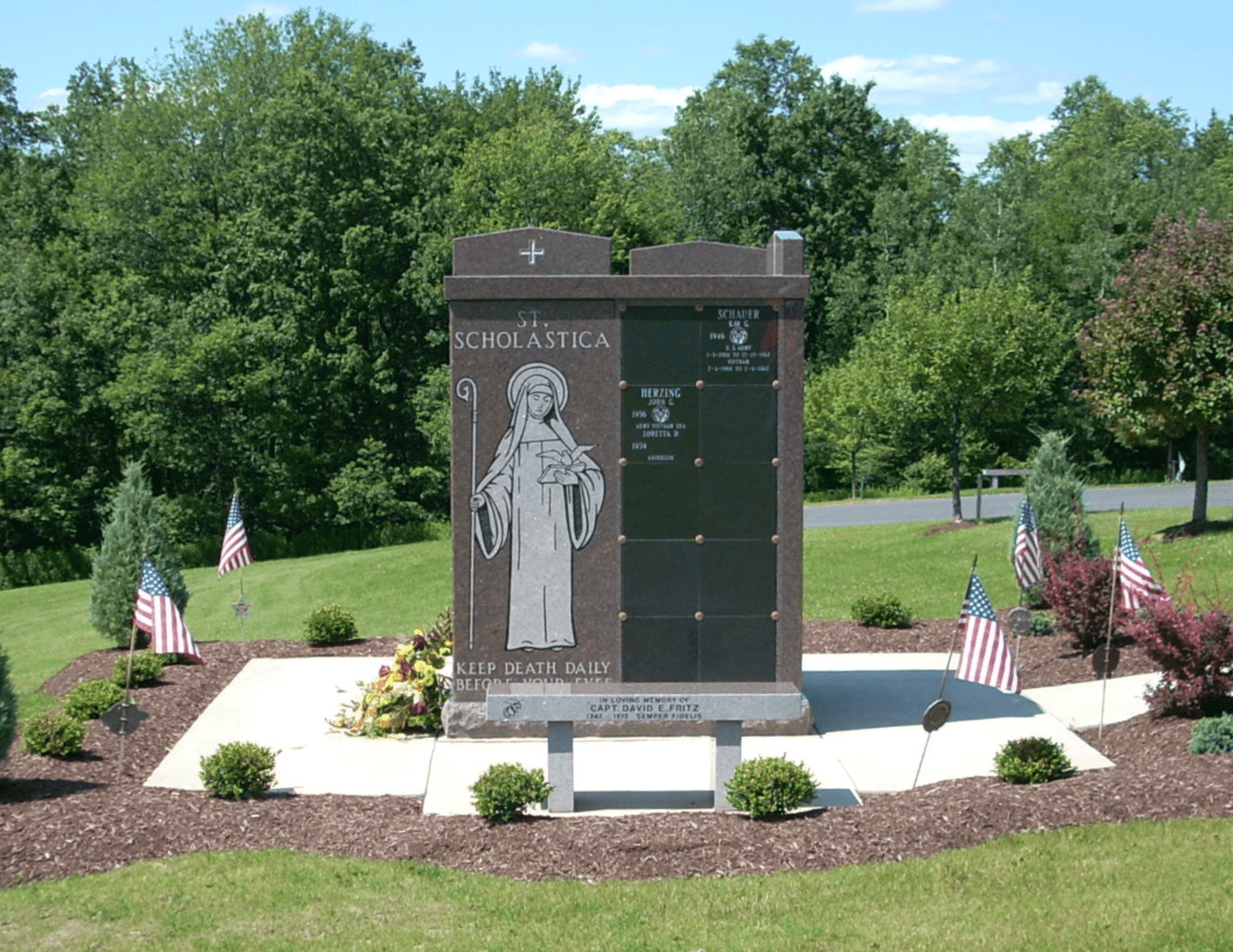 A monument in the middle of a park with flags.