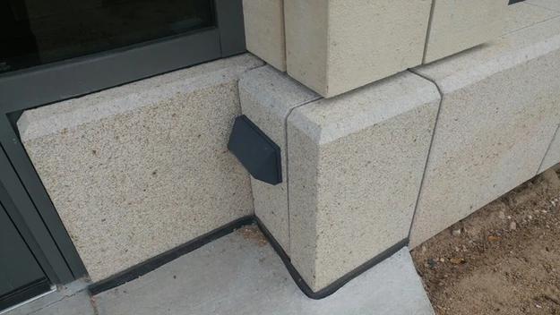A corner of a building with a black metal object on it.