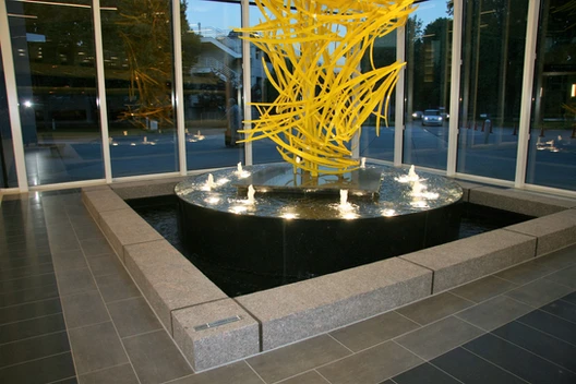 A fountain with yellow sculpture in the middle of it.