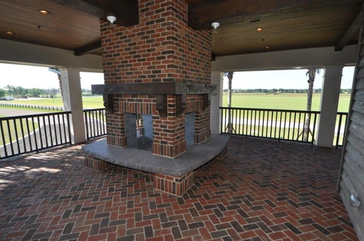 A brick fireplace in the middle of an outdoor patio.