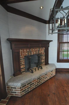 A fireplace with brick and stone surround in the corner of a room.