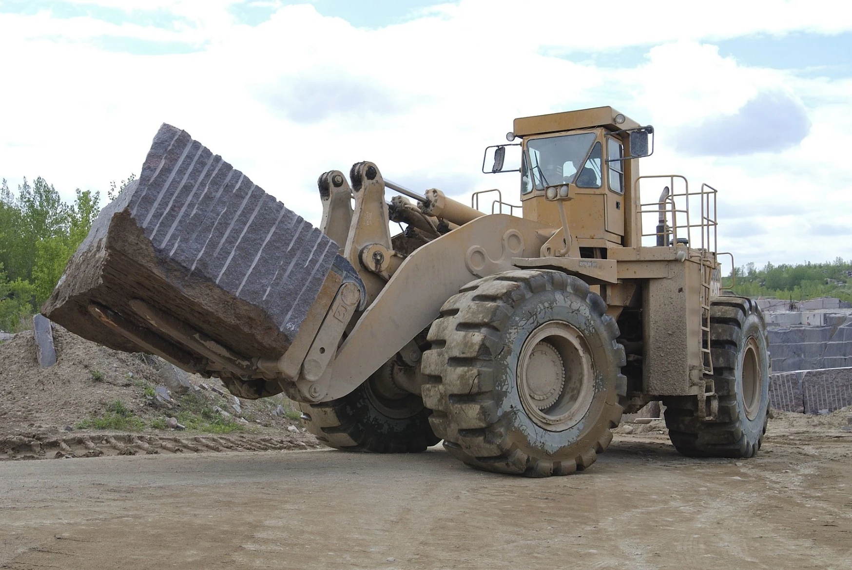 A large wheel loader is dumping rocks into the ground.