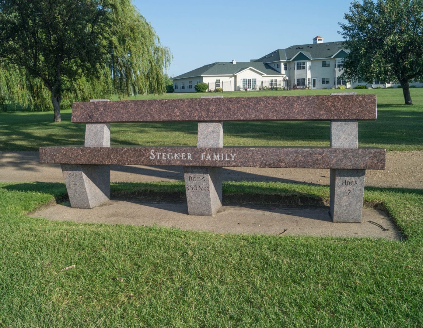 A bench in the middle of a park with grass