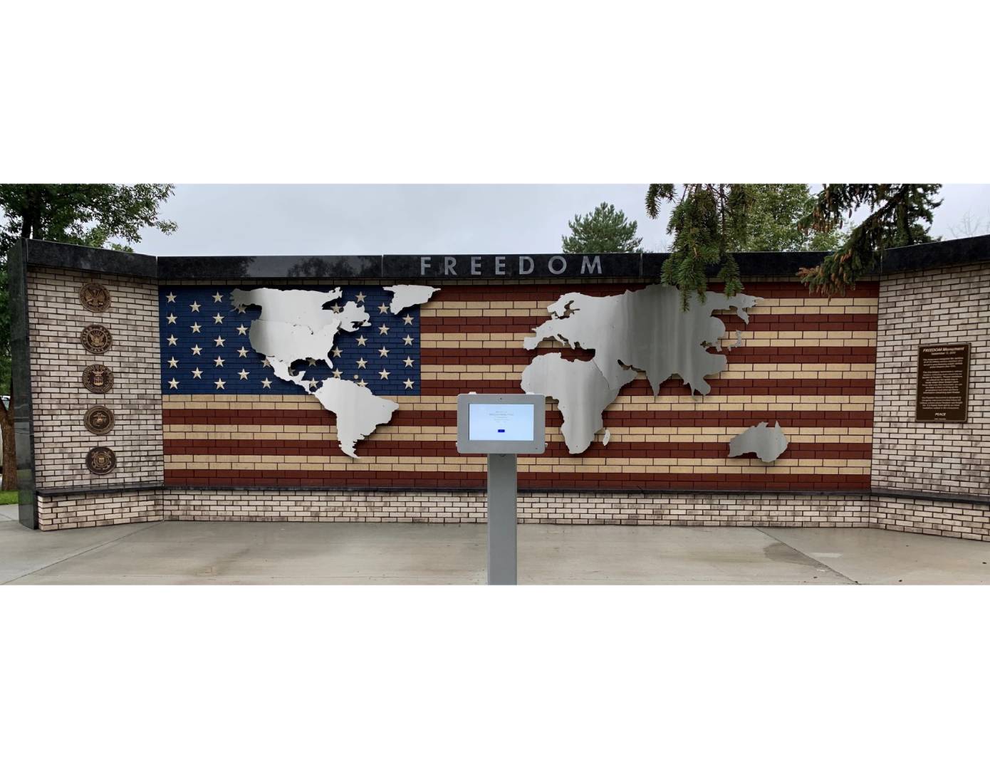 A large metal wall with an american flag and world map on it.