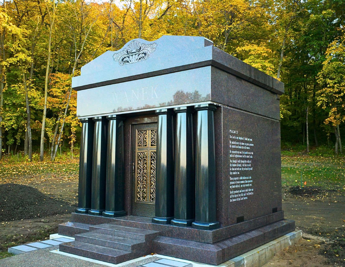 A monument with pillars and steps in front of trees.